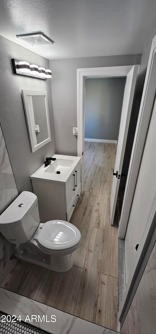 bathroom with hardwood / wood-style flooring, vanity, toilet, and a textured ceiling