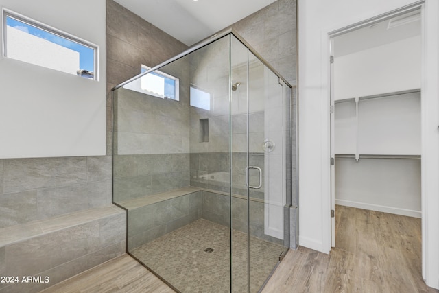 bathroom with hardwood / wood-style flooring and a shower with shower door