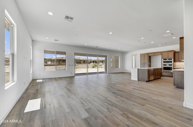 unfurnished living room with light hardwood / wood-style flooring and sink