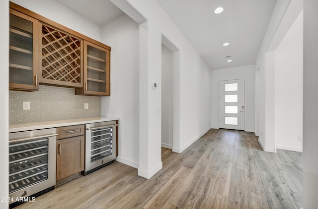 bar with decorative backsplash, light hardwood / wood-style flooring, and wine cooler