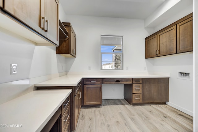 kitchen featuring dark brown cabinetry, light hardwood / wood-style flooring, and built in desk