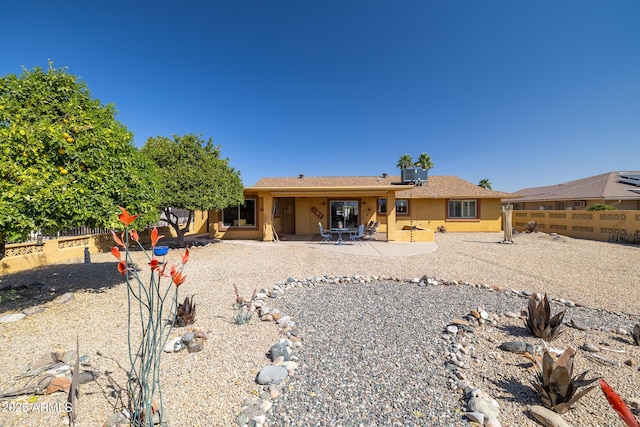 view of front facade with central air condition unit, a patio area, a fenced backyard, and stucco siding