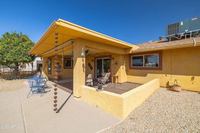 rear view of property featuring stucco siding, fence, and a patio