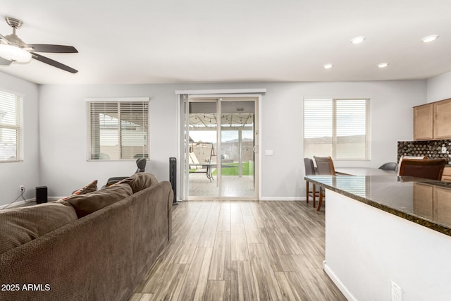 living room featuring recessed lighting, light wood-style flooring, baseboards, and a healthy amount of sunlight