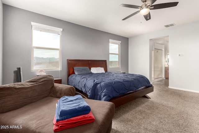 carpeted bedroom with visible vents, baseboards, ensuite bath, and a ceiling fan