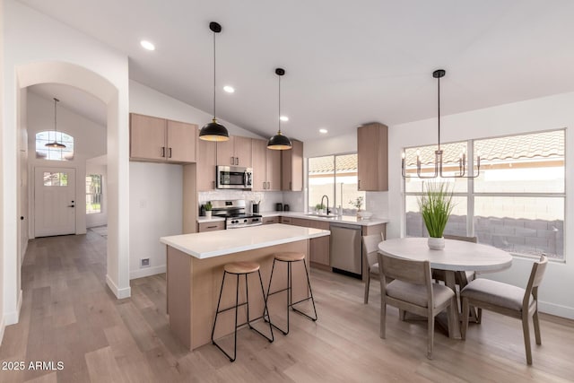 1627 W Maplewood St, Chandler, AZ 85286 - kitchen featuring appliances with stainless steel finishes, a sink, a kitchen island, decorative backsplash, and light wood-style flooring