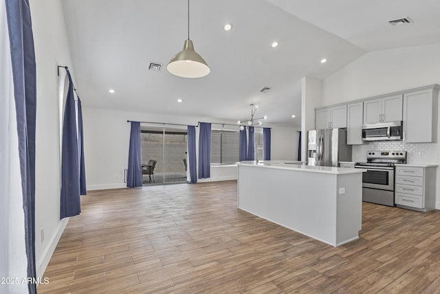 4632 E Kachina Trl, Phoenix, AZ 85044 - kitchen featuring appliances with stainless steel finishes, light countertops, tasteful backsplash, an island with sink, and light wood-type flooring