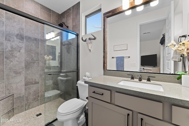 bathroom featuring toilet, a stall shower, visible vents, and vanity