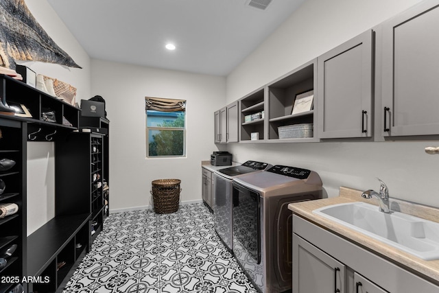 washroom featuring cabinet space, visible vents, baseboards, washer and clothes dryer, and a sink