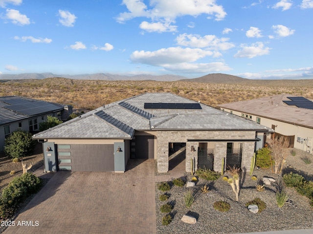 view of front of home featuring a garage, decorative driveway, a mountain view, and roof mounted solar panels