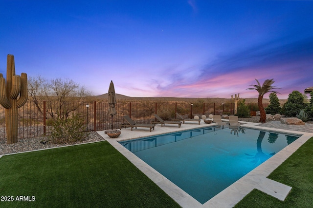 pool at dusk with a fenced backyard, a fenced in pool, a patio, and a yard