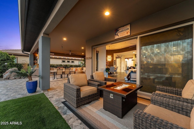 patio terrace at dusk with outdoor dining space and an outdoor living space with a fire pit