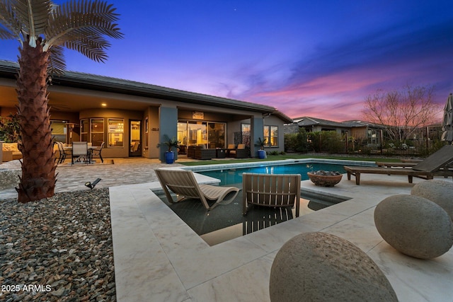 pool at dusk featuring an outdoor pool, outdoor lounge area, and a patio