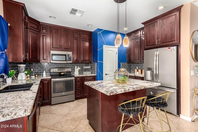 kitchen with appliances with stainless steel finishes, a center island, decorative light fixtures, and tasteful backsplash