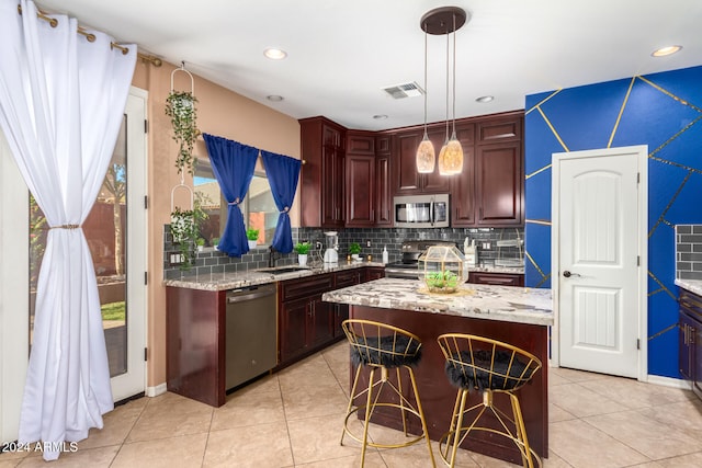 kitchen with light stone countertops, tasteful backsplash, stainless steel appliances, a center island, and hanging light fixtures