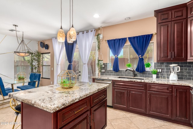 kitchen with sink, hanging light fixtures, stainless steel dishwasher, backsplash, and light tile patterned floors