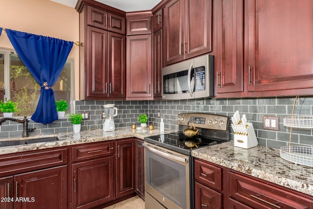 kitchen with decorative backsplash, sink, light stone counters, and appliances with stainless steel finishes