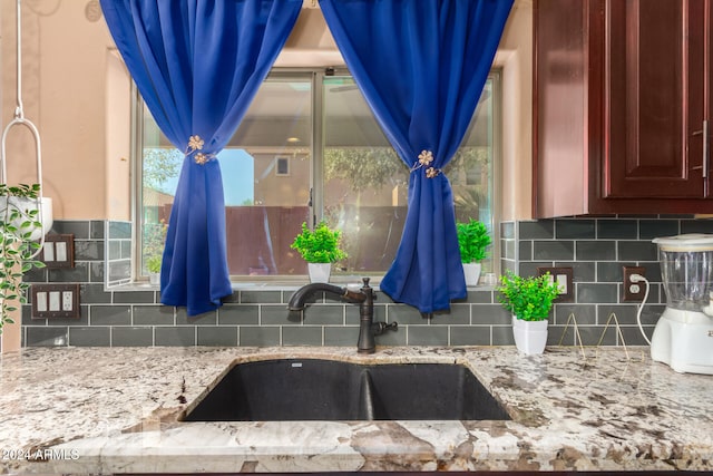 kitchen with light stone countertops, tasteful backsplash, and sink