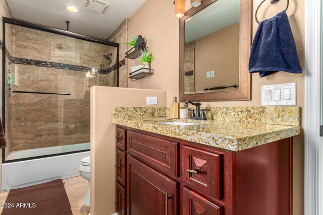 full bathroom with tile patterned floors, vanity, enclosed tub / shower combo, and toilet