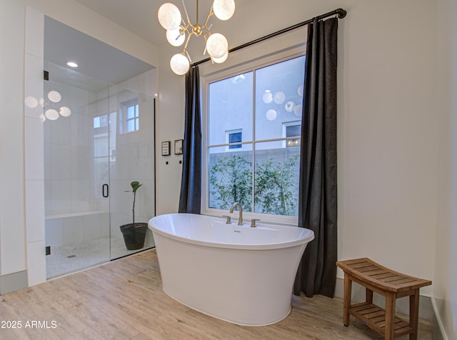 bathroom with wood-type flooring, separate shower and tub, and a notable chandelier