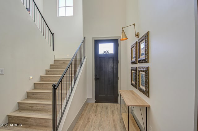 foyer featuring a towering ceiling and light hardwood / wood-style floors