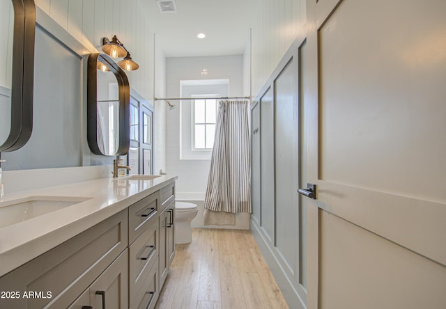 full bathroom with vanity, hardwood / wood-style floors, shower / tub combo, and toilet