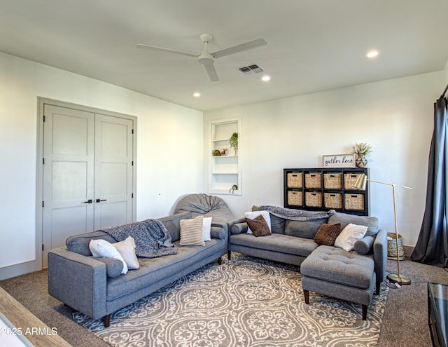 carpeted living room featuring ceiling fan and built in shelves