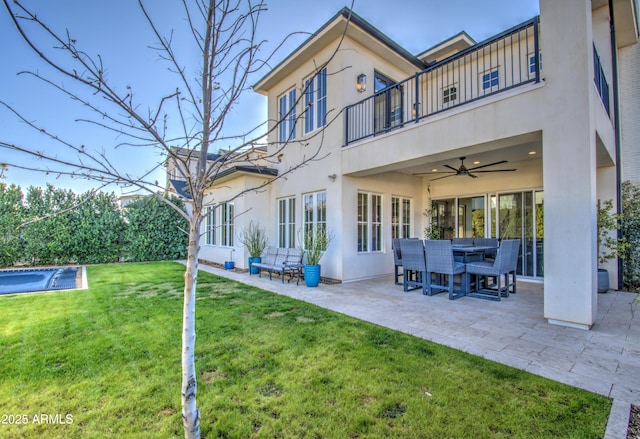 back of house featuring ceiling fan, a patio area, a balcony, and a lawn