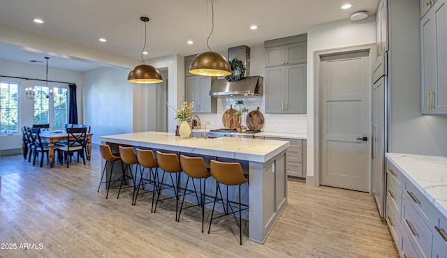 kitchen featuring decorative light fixtures, a breakfast bar area, gray cabinetry, light stone counters, and a spacious island