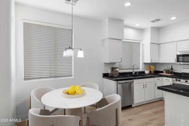 kitchen featuring sink, white cabinetry, hanging light fixtures, appliances with stainless steel finishes, and light hardwood / wood-style floors