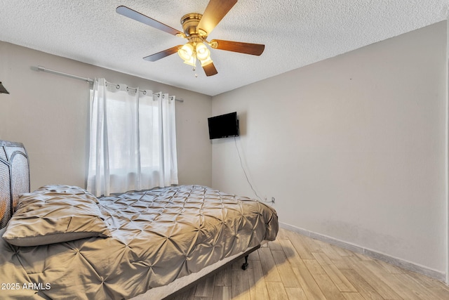 bedroom with ceiling fan, light hardwood / wood-style flooring, and a textured ceiling