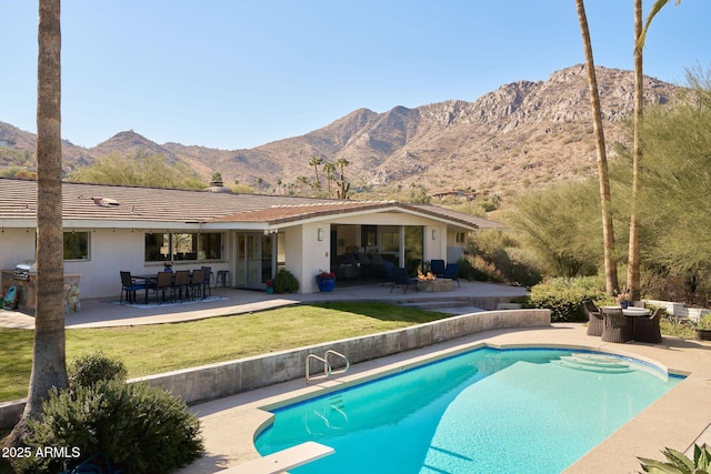 view of swimming pool featuring a mountain view, a yard, a diving board, and a patio