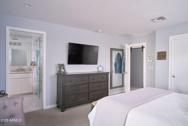 bedroom featuring ensuite bath, a barn door, light carpet, and sink