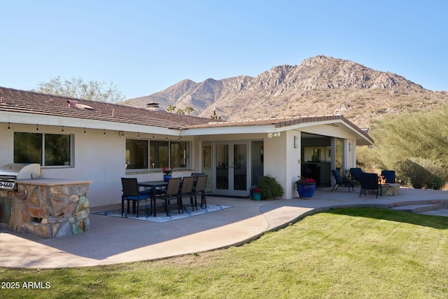 back of property featuring a mountain view, a yard, french doors, and a patio