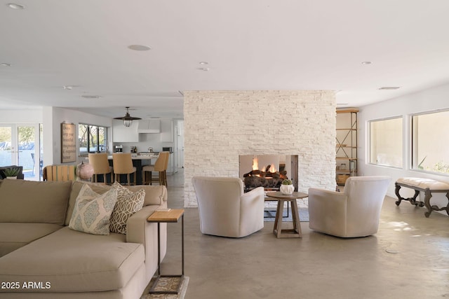 living room with ceiling fan and a stone fireplace