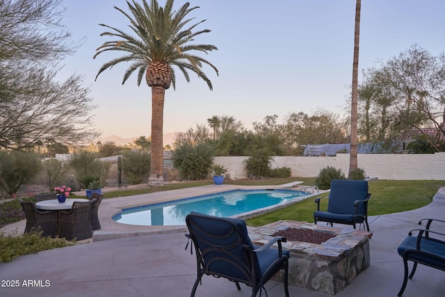 pool at dusk with an outdoor fire pit, a diving board, and a patio