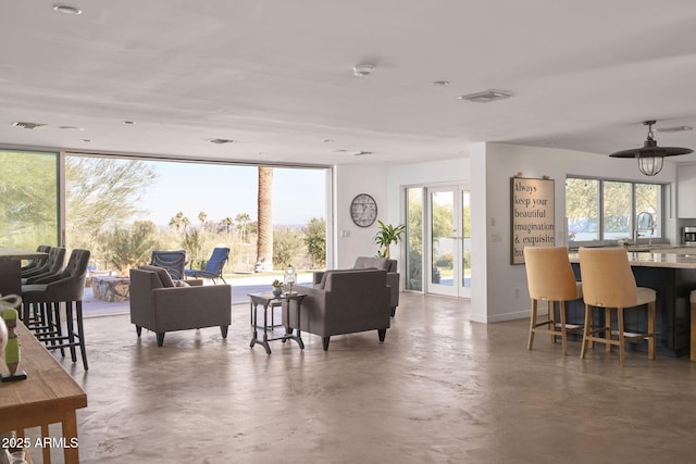 living room featuring concrete floors, floor to ceiling windows, plenty of natural light, and sink