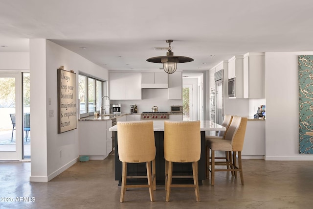 kitchen featuring a kitchen island, white cabinets, a breakfast bar, and built in appliances