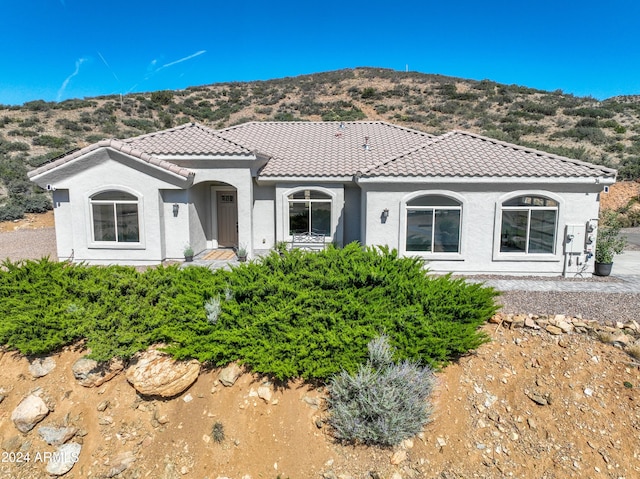 mediterranean / spanish house featuring a tile roof, a mountain view, and stucco siding