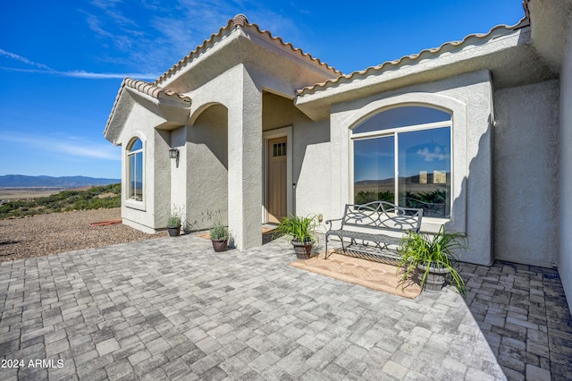 view of exterior entry featuring a mountain view and a patio