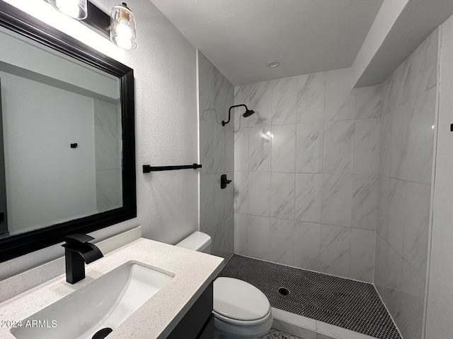 bathroom with toilet, vanity, and a tile shower