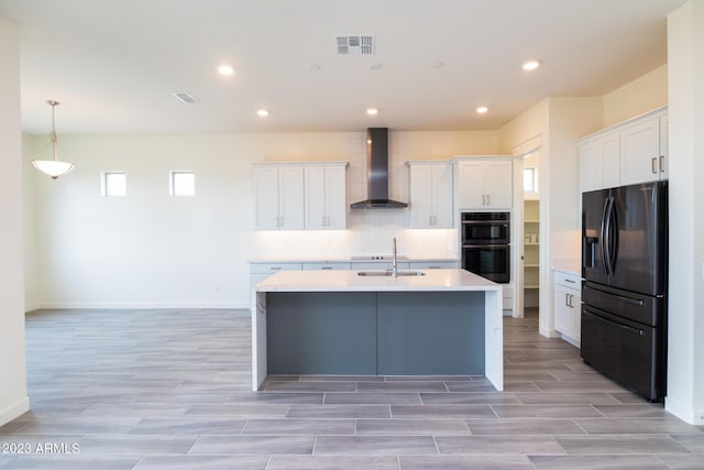 kitchen with wall chimney exhaust hood, sink, black appliances, decorative light fixtures, and white cabinetry