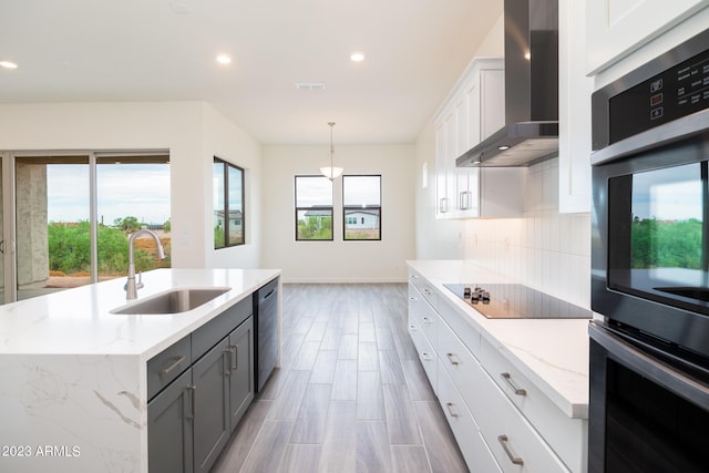 kitchen with wall chimney exhaust hood, sink, pendant lighting, a center island with sink, and white cabinetry