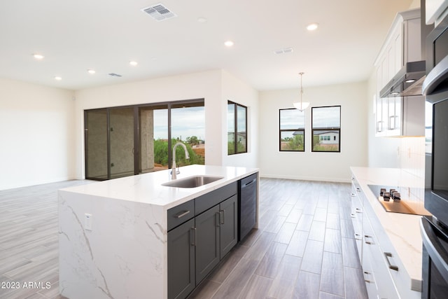 kitchen with sink, decorative light fixtures, black electric cooktop, a kitchen island with sink, and white cabinets