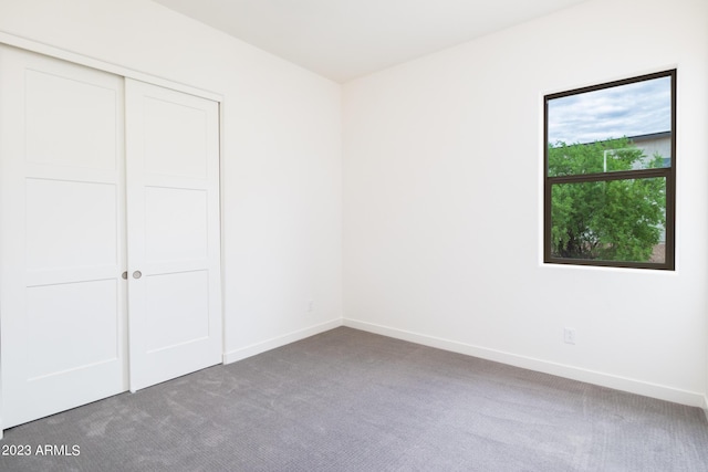 unfurnished bedroom featuring a closet and dark colored carpet