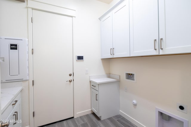 laundry area with electric panel, hookup for a washing machine, cabinets, and hookup for an electric dryer