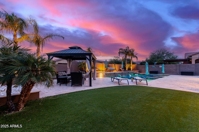 pool at dusk with a gazebo, a yard, and a patio area