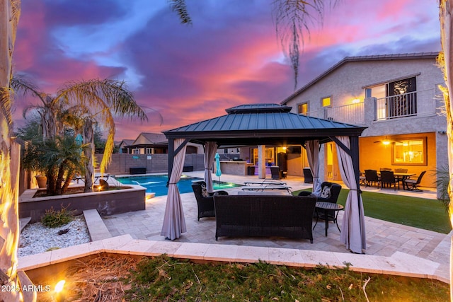 pool at dusk featuring a gazebo, outdoor lounge area, and a patio