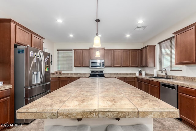 kitchen featuring a breakfast bar, pendant lighting, sink, a center island, and stainless steel appliances