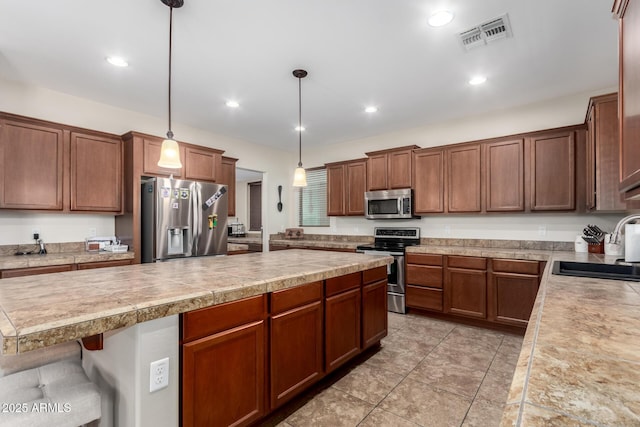 kitchen with pendant lighting, sink, light tile patterned floors, stainless steel appliances, and a kitchen breakfast bar